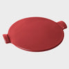 A round burgundy red ceramic pizza stone with two protruding handles on the sides.