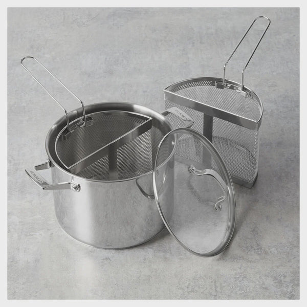 Stainless steel pot with lid and strainer on a gray concrete surface