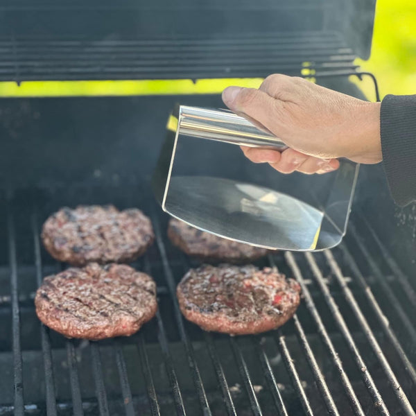 Person using a burger smasher to grill patties.