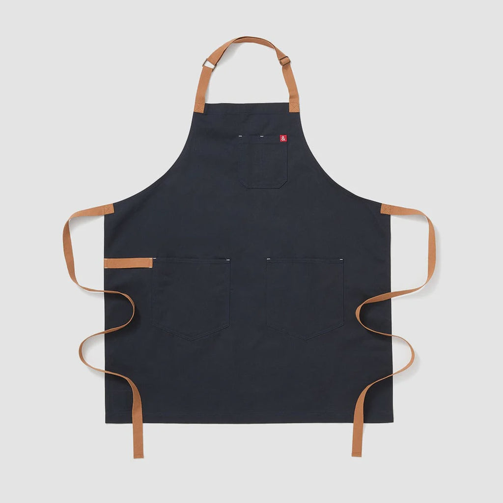 A midnight cider blue apron with leather straps and pockets, displayed against a white background.