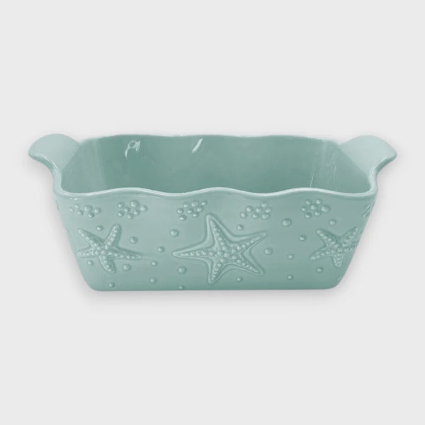 Mint green ceramic loaf pan with starfish design on a white background